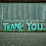 Two boards propped against a wall with the words "thank you" painted on them.